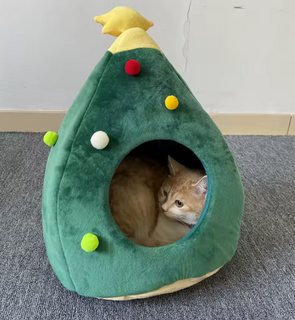 Gato descansando en su cama navideña en forma de árbol.